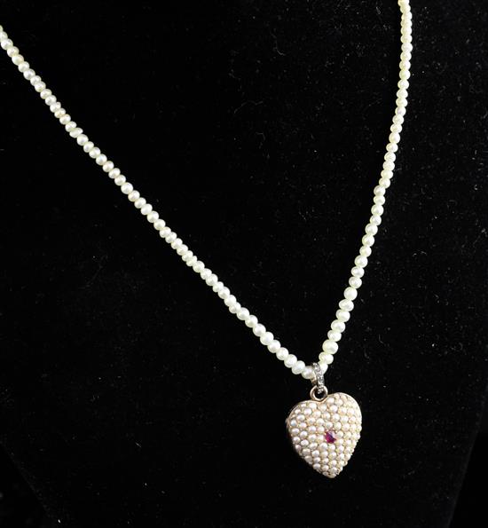 An early 20th century gold, ruby and split pearl set heart shaped pendant locket, pendant inc. bale 1in.